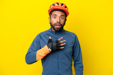 Young cyclist Brazilian man isolated on yellow background surprised and shocked while looking right