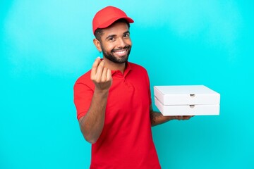 Pizza delivery Brazilian man with work uniform picking up pizza boxes isolated on blue background...