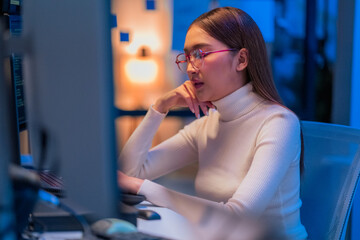 asian female programmer sits a dark tech workspace at night, fully focused on developing an online...