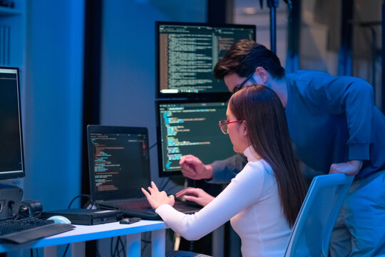 Asian programmers collaborating on software development at night, focused on writing code across multiple monitors in a tech office environment  Programmers Collaborating on Software Development 