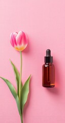 Pink background, tulip, and amber dropper bottle.  A single, vibrant pink and white tulip sits beside a small, amber glass dropper bottle on a smooth, solid pink surface. 
