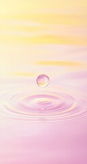 A single, clear water droplet hangs suspended above a gentle ripple effect on a pastel pink and yellow surface