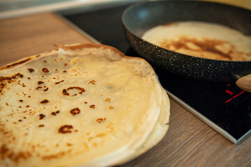 Delicious homemade crepes being cooked on a stove top, with a close-up of a plate full of freshly...
