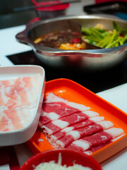 Sliced Meat and belly pork in tray for shabu or Sichuan mala hotpot on restaurant table.