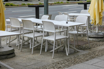 Empty White Outdoor Cafe Tables and Chairs on Stone Pavement During Off-Hours