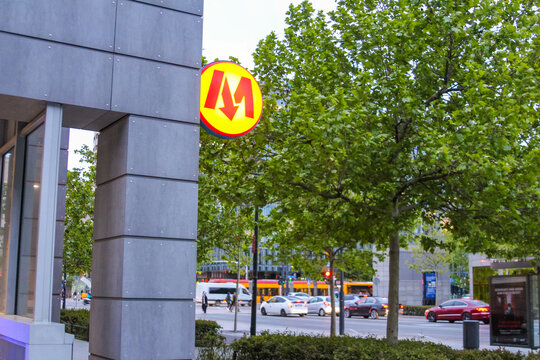 McDonald's Golden M Logo on Building Exterior with Green Trees and Urban Setting