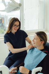 Smiling mature woman at dental check-up with young female dentist. Appointment at clinic. Tooth whitening, cleaning or oral, mouth and gum care at hospital. Soft focus. Part of a series. Close-up