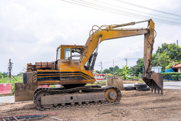 Old excavator or backhoe full of traces wear and tear and rust from use many years parked under bridge ready for use in road improvement and repair work.