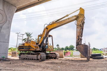 Old excavator or backhoe full of traces wear and tear and rust from use many years parked under bridge ready for use in road improvement and repair work.
