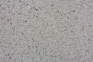 A rough, speckled surface features a mix of gray and black tones, creating a gritty appearance. Its uneven distribution of dark flecks adds depth and interest to the predominantly light background.