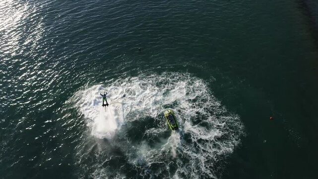 freestyle on water. man riding a jet ski. man flying on a flyboard behind a jet ski on the sea, drone view