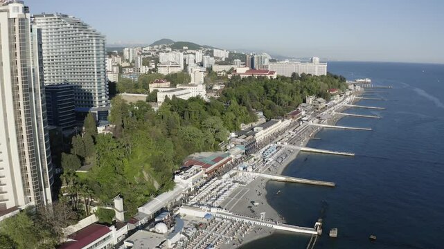 Sea coast along the city view on a summer day from the air. Embankment of the city of Sochi view from a drone on a summer day