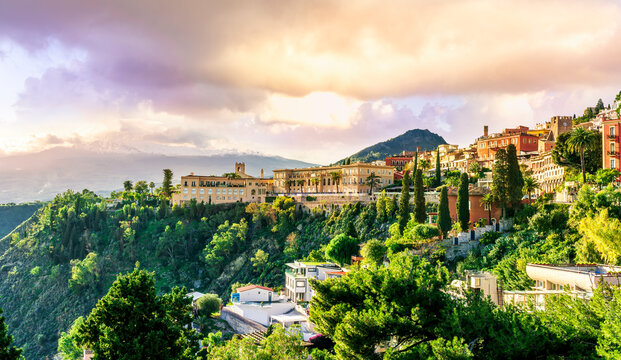 Amazing landscape of a beautiful mountain town Taormina in Sicily, Italy. Scenic view from a green mountain to a beautiful famous hotel and high majestic mount vulcan Enta in snow.