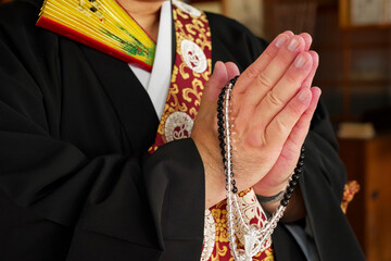 お寺の本堂で合掌をするお坊さん