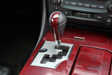 Close up Automatic gear stick of a modern car interior with wood. Black leather car interior....