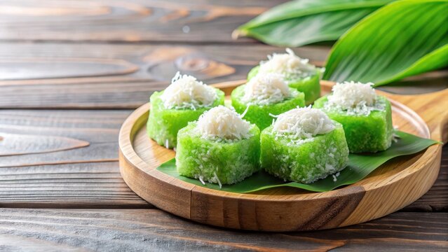 Steamed kuih ketayap with shredded coconut and pandan flavor on a wooden plate