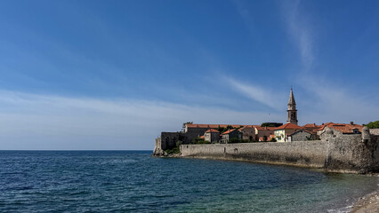  Coastal view of historic town with stone walls and church tower Budva, Montenegro.