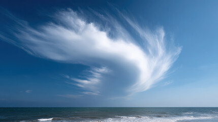 Fototapeta premium Large, swirling cloud formation over calm ocean clear blue sky creates peaceful yet dynamic
