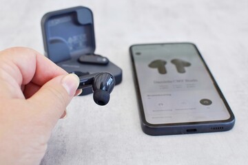 The earbuds are connected to a mobile phone.