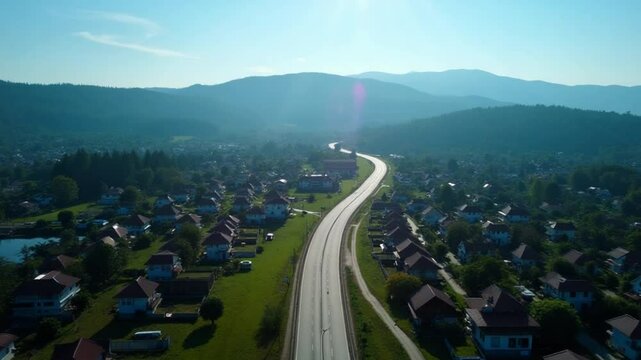 Aerial landscape of 4 lane road with residential area, forest, mountain, blue sky and sunlight with high angle view of main road from Drone shot in Tak province, northern countryside of Thailand.
