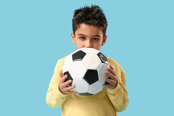 Cute little boy with soccer ball on blue background