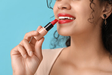 Young African-American woman with red lipstick on blue background, closeup