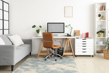 Interior of light living room with workplace, sofa and shelf unit