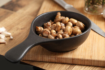 Frying pan with roasted mushrooms on wooden table