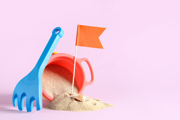 Seashell, sand, flag, toy rake and bucket on pink background