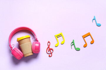 Headphones with cup of coffee and notes on lilac background