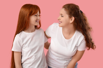 Beautiful young woman with her cute daughter on pink background. Mother's Day celebration