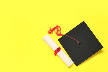 Mortar board and diploma on yellow background