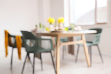 Blurred view of dining table with narcissus flowers in light room