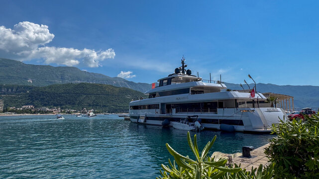 Budva, Montenegro - May 11, 2025: Luxury yacht Aquarius docked in serene bay with mountains and clear blue sky