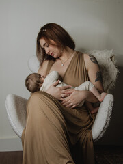 Mère qui allaite son bébé sur un fauteuil blanc