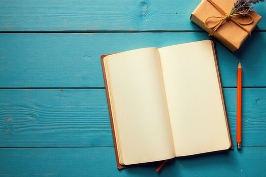 Open notebook with blank pages, a small gift, and a pencil on a blue wooden surface, ready for ideas and notes