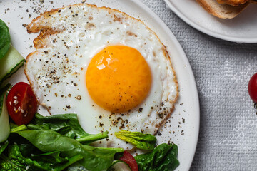 Fried egg with spinach, tomato and cucumber salad in a white plate. Healthy breakfast