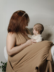 Mère avec son bébé dans les bras sur un fauteuil blanc en studio