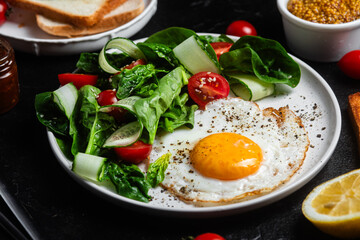 Fried egg with spinach, tomato and cucumber salad in a white plate. Healthy breakfast