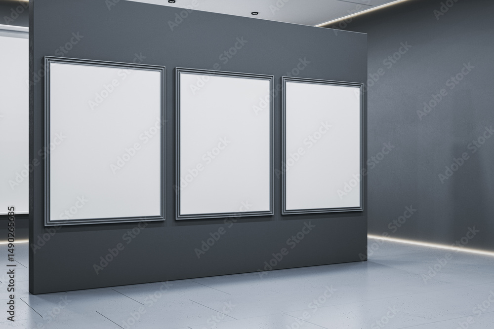 Poster three blank vertical poster frames on dark partition wall in modern exhibition gallery room with cle