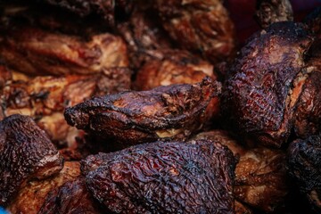 A close-up of freshly grilled meat pieces stacked together, featuring crispy, charred edges and tender, juicy textures ideal for BBQ and culinary visuals.