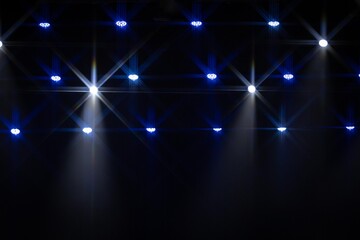 A dramatic array of yellow and purple stage lights creates vivid starburst patterns in the dark,...