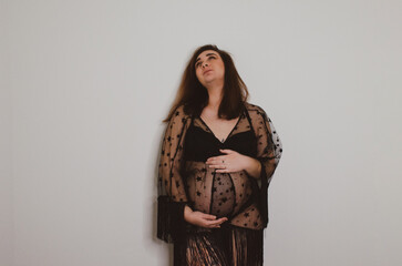 Femme enceinte en sous vêtement noir sur fond blanc