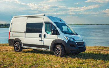 white camper van on hill with grass and sea view with sky