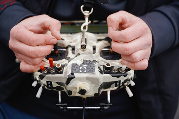 drone operator adjusting remote control outdoors. close-up of hands skillfully maneuvering advanced...