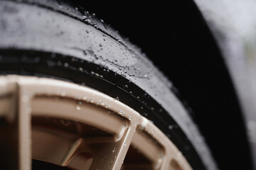 close-up of car tire with water droplets highlighting rubber texture and wheel design, perfect for...