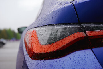 close-up of car taillight in rainy weather, emphasizing sleek design and water droplets detail....
