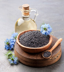Black cumin oil in a bottle and nigella seed with flower