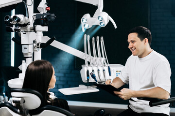 Dentist consulting with patient before dental procedure in a modern clinic, discussing oral health...