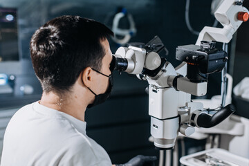 In a dental clinic, a dentist uses a microscope to treat a patient's teeth. Concept of medicine, dentistry and health care.